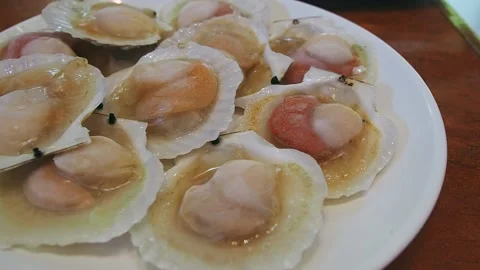 Panning left of raw shellfish or raw scallops on white dish. Stock Footage 146822703