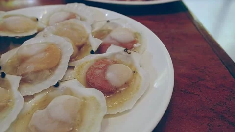 Panning left of raw shellfish or raw scallops on white dish. Stock Footage 154507449
