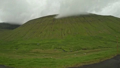 Panning left shot of a massive green mountain with cloudy peak, Faroe Islands Stock Footage 340005302