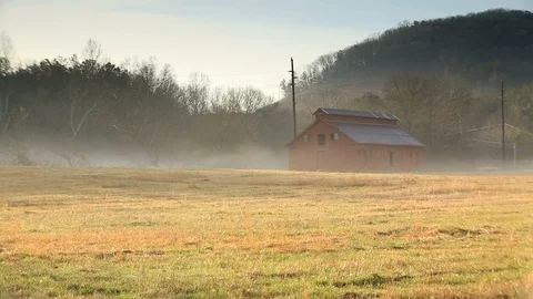 Panning left view of red barn in large field covered in fog. Stock Footage 85957962