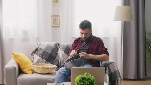 Panning of man sitting on sofa and knitting Video stock 107350455