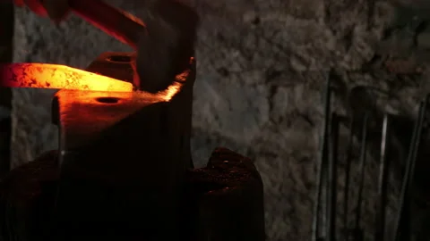 Panning motion of two blacksmiths hammering on an anvil forging Stock Footage 167861028