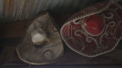Panning old sombreros hanging in rustic wall Stock Footage 171543387