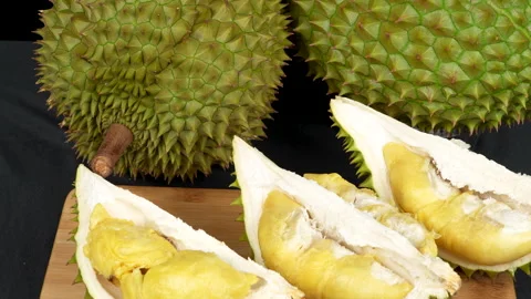 Panning opened Ri6 durian next to whole fruits on black background. Vídeo Stock 335083986