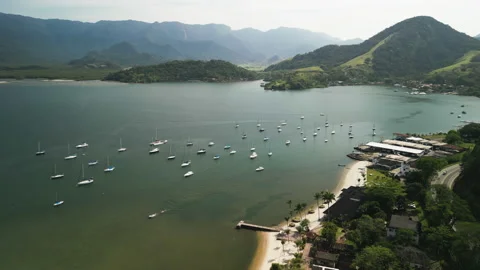 Panning Over Beachfront Beach, Overlooking Sailboats, Mountains and Forests, 4k Stock Footage 239685914