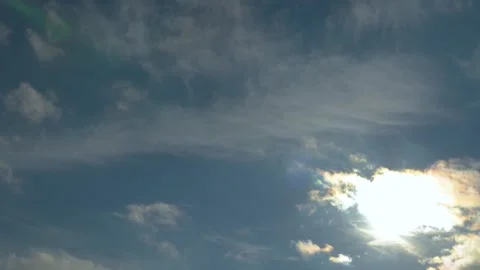 Panning over blue sky with clouds against sun with lens flares and flying bir Stock Footage 144978689