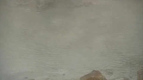 Panning over pool of bubbling water, somewhat obscured by steam. Stock Footage 86754642