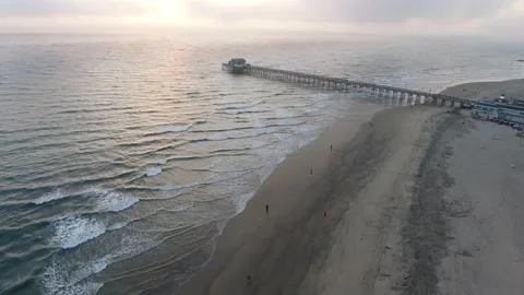 Panning over rolling waves along the coast at sunset by pier Stock Footage 157140508