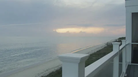 Panning over white railing of beach house to stormy pink sunset in Virginia Stock Footage 204098780