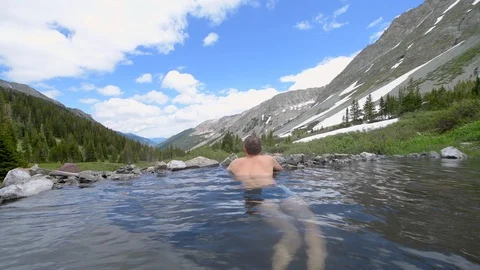 Panning pov view of man sitting swimming in Conondrum hot springs Colorado Stock Footage 120608596