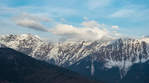 Panning to the right. Clouds above mountains covered with snow. Stock Footage 150140232