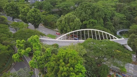 Panning right shot of a uniquely shaped pedestrian bridge above a busy road Stock Footage 108801837