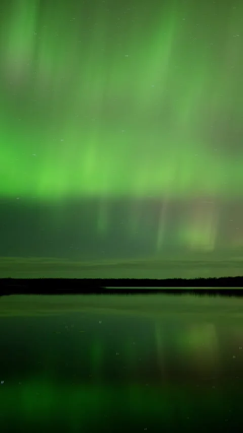 Panning to the right of a time lapse of northern lights reflecting in a lake Stock Footage 296657143