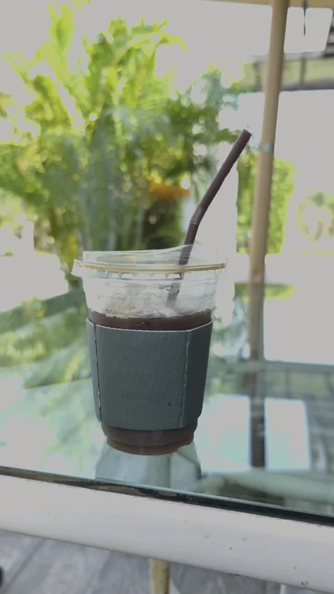 Panning right video view of iced black Americano coffee in plastic takeaway. Video stock 328818543