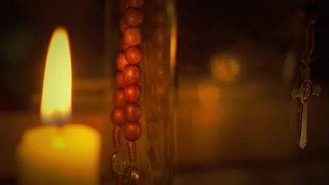 Panning selective focus shot of a Saint Benedict rosary beside the candle Stock-Footage 163921095