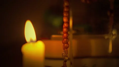 Panning selective-focus shot of a Saint Benedict rosary beside the candle Stock-Footage 163921482