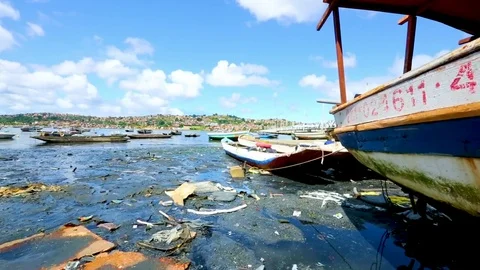 Panning shot across a lake littered with garbage and wrecked boats Stock Footage