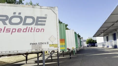 Panning Shot Along Freight Containers Toward Warehouse Loading Bays in Weil am Stock Footage 343890738