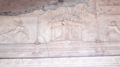 Panning shot of a bas relief of two cupids on a bath house wall at pompeii Stock Footage 137087560