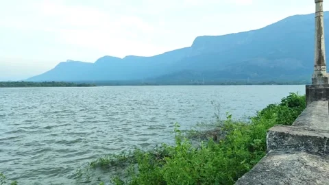 Panning Shot of Chulliyar Dam Lakefront with Stone Railing and Blue Mountai.. Stock Footage 329178432