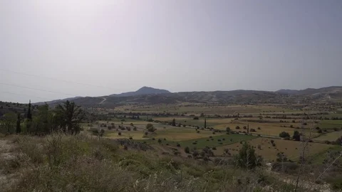 Panning shot of countryside with fields, farms and wind turbines on a hill Stock Footage