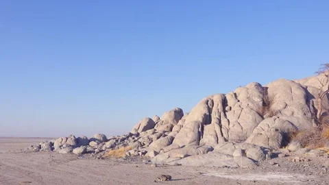 Panning shot from desolate salt flat to rocky outcrop with baobab Stock Footage 81416556
