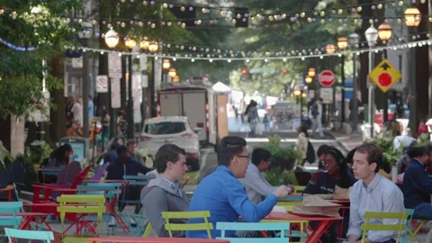 A panning shot of a diverse crowd of young professionals eat lunch, relax Vidéo 133453750