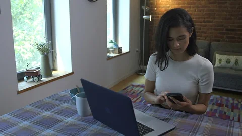 Panning shot of female freelancer using laptop and phone while working from home Stock Footage 114854940