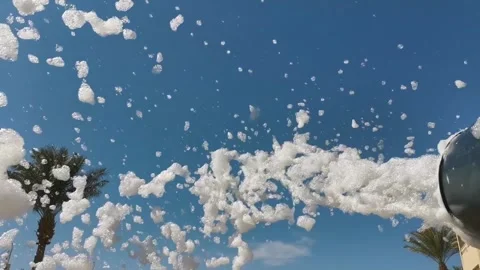 Panning shot of foam cannon spraying bubbles and suds across sunny palm lin.. Stock Footage 329871023