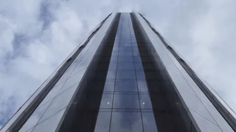 A panning shot of a glass skyscraper reflecting clouds. Stock Footage 289880359