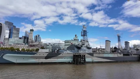 Panning shot of HMS Belfast on River Thames with City skyline backdrop Stock Footage 346677347