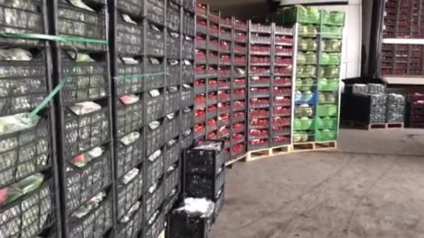 A panning shot inside a large warehouse or cold storage facility showing stacks Stock Footage 333376693