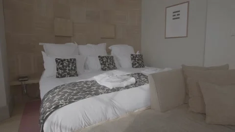 Panning shot of large white bed in hotel room/bedroom Stock Footage 202133343