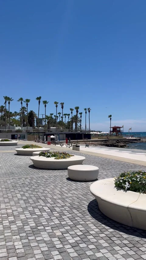 Panning shot from left to right showing round flower beds on a sea promenade Stock Footage 337366721