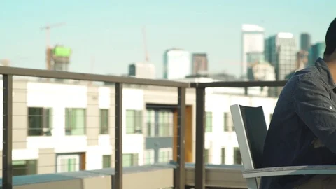 Panning shot of man using a laptop outside Stock Footage 76540436