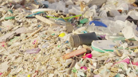 Panning shot of microplastics and plastic waste in sand on a beach Stock Footage 336491243