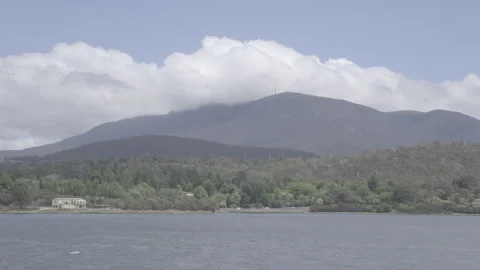 Panning Shot of Mountain Lake with Dramatic Cloud Movement and Forested Shore Stock Footage 328193367