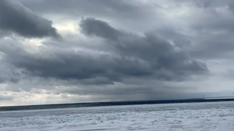 Panning shot of moving storm clouds over a frozen lake in winter landscape Stock Footage 325477798