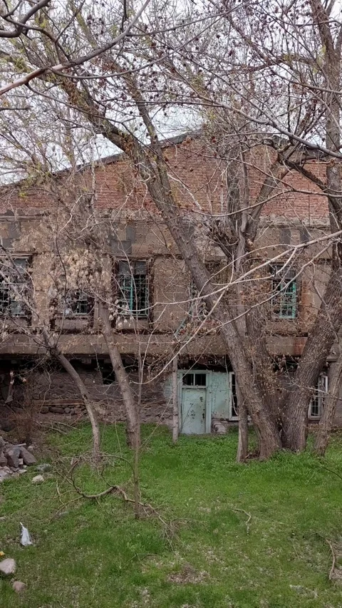 Panning shot of an old rustic stone building with trees and grassy yard Stock Footage 345667318
