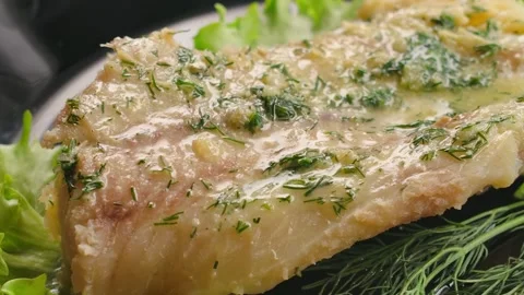 Panning shot over a cooked cod fillet with melting garlic butter Stock Footage 314625278