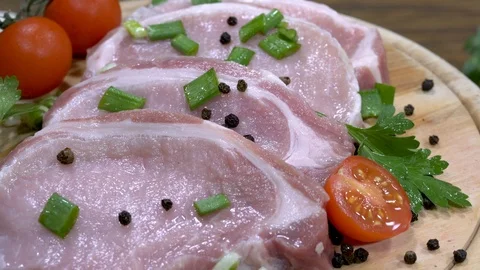 Panning shot over raw steaks on a rotating wooden plate Stock-Footage 88253940