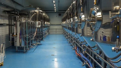 Panning shot of rows of large steel tanks with beer in industrial brewery plant Video stock 127312379