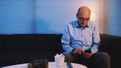 Panning shot of senior man looking at the screen on his mobile phone at night Stock Footage 99013828