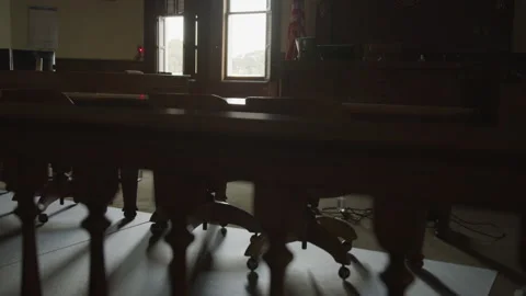 Panning shot of shadows casted upon a table in an abandoned courtroom Stock Footage 208789224