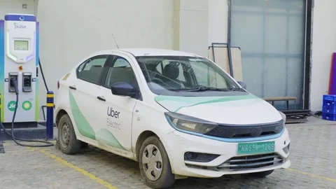 Panning shot showing a Uber electric Tata car charging at a Jio BP Pulse DC fast Stock Footage 333009253