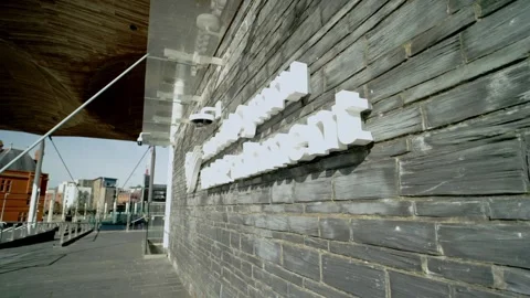 Panning shot of sign outside the Welsh Parliament Senedd Assembly building Vídeo Stock 333010501