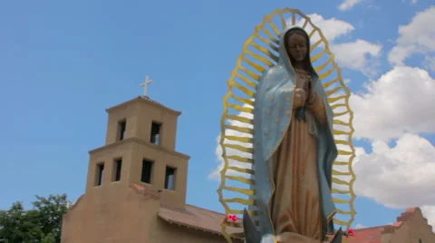 Panning shot of a Statue of Our Lady of Guadalupe in front of an Adobe Church Stock Footage 64834554