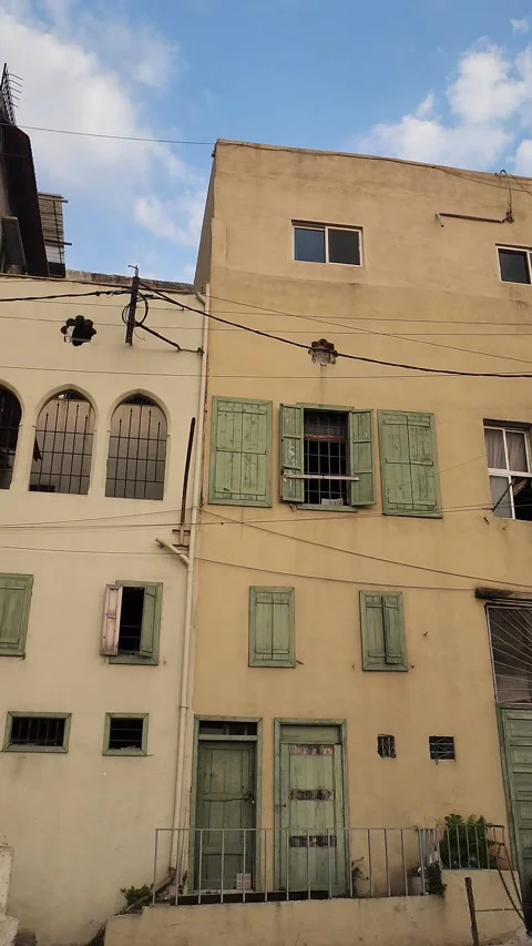 A panning shot of two adjacent buildings with green doors and shutters Stock-Footage 314172665