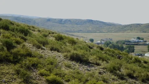 Panning shot of view down into sunny valley from hilltop of remote village Stock Footage 122598397
