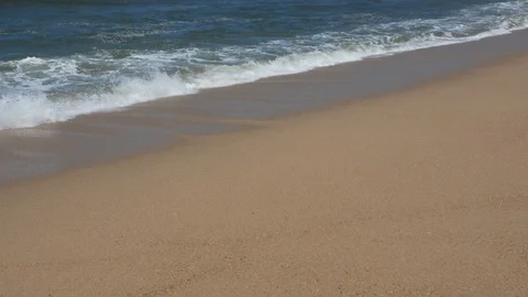 Panning shot of waves breaking on sandy beach as water flows over the sand Stock Footage 108194982